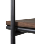 Close-up of the Ethnicraft Oscar Hanging Rack corner, featuring a thick FSC-certified teak shelf supported by black metal cylindrical rods and a vertical frame, highlighting minimalist and industrial design elements.
