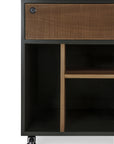 Close-up of the Ethnicraft Oscar Drawer Unit, featuring a textured solid teak wood drawer, open shelves, and caster wheels. The modern design combines contrasting black and natural wood tones, making it an ideal choice for stylish office storage.