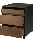 The Ethnicraft Oscar Drawer Unit - Teak - Black is a wooden filing cabinet on wheels with three drawers; the bottom features a grooved, textured solid teak front.