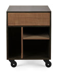 The Ethnicraft Oscar Drawer Unit - Teak - Black is a compact wooden cabinet on wheels, with a textured top drawer and open shelves below divided into three sections of different sizes.