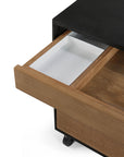A close-up of the Ethnicraft Oscar Drawer Unit - Teak - Black shows its white compartmentalized interior, partially pulled out from the black solid teak cabinet, which features small wheels for easy movement.