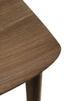 Close-up of an FSC-certified solid teak table with smooth finish and visible grain, showing the tabletop and one leg—pairs perfectly with the Ethnicraft Bok Dining Chair in Natural Teak.