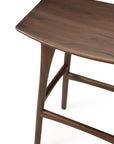 A close-up of the Ethnicraft Osso Barstool - Teak, crafted from FSC-certified teak with a smooth curved seat and tapered legs, is shown against a white background.