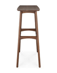 The Osso Barstool - Teak by Ethnicraft features a tall, rectangular FSC-certified teak seat with angled legs and horizontal supports, shown from the front.