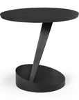 The Oblic Side Table - Black by Ethnicraft features a modern, minimalist design with a round wooden top, angled central support, and oval base. Its clean lines and geometric form make it perfect for lovers of sculptural side tables.
