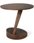 The Oblic Side Table - Teak by Ethnicraft features a round top, slanted center support, and oval base in dark FSC-certified teak—a sculptural, modern piece perfect for those who appreciate distinctive side tables.