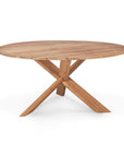 The Circle Outdoor Dining Table by Ethnicraft is a round table in natural teak with a unique crossed-leg base, crafted from FSC certified wood.