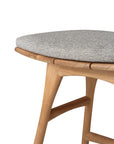 Close-up of the Ethnicraft Osso Outdoor Stool with cushion, featuring a curved teak frame, round light gray upholstered seat, smooth natural finish, and clean modern lines from the outdoor collection.