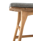Close-up of the Ethnicraft Osso Outdoor Stool with cushion, showing light teak wood and a textured gray seat. The image emphasizes the stool’s modern, minimalist design against a white background.