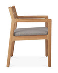 Side view of the Ethnicraft Jack Outdoor Dining Chair - Teak, featuring angled legs, open armrests, and a padded gray outdoor seat cushion. This minimalist chair showcases classic European refinement with clean lines and a natural teak finish.