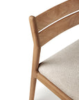 Close-up of the Ethnicraft Jack Outdoor Dining Chair - Teak (without armrest), highlighting its curved backrest, natural wood grain, and light textured outdoor seat, exemplifying smooth craftsmanship.