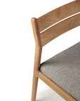 A close-up of the Ethnicraft Jack Outdoor Dining Chair - Teak (without armrest) showcases its curved backrest and light gray seat cushion in outdoor fabric, crafted from solid teak and set against a white background.