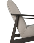 Side view of the Ethnicraft Aspekt Lounge Chair - Dark Brown Teak, featuring light beige upholstery and a dark teak frame with angular, minimalist lines inspired by Ethnicraft’s design.