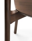 Close-up view of the leg and underside of an Ethnicraft Bok Dining Chair in Brown Teak, featuring smooth rounded edges, rich brown finish, visible joinery, and FSC-certified teak wood grain details.