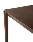 A close-up of the Ethnicraft Bok Dining Table - Brown Teak highlights its smooth, FSC-certified solid teak surface and tapered legs against a white background.