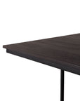 Close-up of the Tacet Dining Table by Ethnicraft, highlighting its dark teak top and black metal leg against a white background.