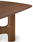 Close-up of an Ethnicraft Flow Dining Table | Teak Wild Brown, featuring a brown wood surface with a smooth, rounded corner and a sculptural, curved pedestal base.