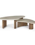 Two Ethnicraft Boomerang Outdoor Coffee Tables, featuring asymmetrical off-white concrete tops and cylindrical reclaimed teak bases, are placed together on a white background.