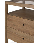 A close-up of the Ethnicraft Spindle Dresser - Teak, crafted from reclaimed FSC teak with a natural finish that highlights its grain, featuring two drawers with round cut-out handles and a glass top surface.