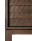 Close-up of the Ethnicraft Sono Cupboard, featuring hand-carved geometric square panels and a sturdy leg. Crafted from solid teak, the cupboard showcases a smooth, dark brown finish.