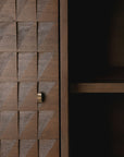 Close-up of the Ethnicraft Sono Cupboard, showcasing hand-carved wooden panels with a geometric textured door, a small metal handle, and an adjacent open shelf featuring a dark empty interior.