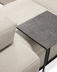 A close-up of the Ethnicraft Mellow Modular Sofa in Off White, upholstered in stain-resistant Italian fabric, paired with a black side table featuring a textured, cracked surface atop the sofa cushion.