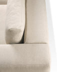 Close-up of the Ethnicraft Mellow Sofa in Off White, showcasing its textured recycled cotton upholstery, a plush cushion, and armrest, with soft lighting casting gentle shadows on the surface.