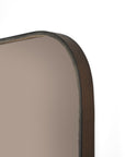 Close-up of the upper corner of Ethnicraft’s Camber wall mirror—square, with a bronze-toned wooden frame and rounded edges—set against a plain white background.