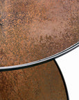 Close-up of two round, bronze-copper Nesting Coffee Tables by Ethnicraft, featuring textured, mottled metal surfaces with slim rims, overlapping against a white background.