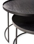 The Ethnicraft Tray Coffee Table - Set of 2 features modern, round black tables with slim metal legs and textured tops, partially nested on a white background—an ideal stylish and customizable coffee table solution.
