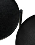 Two overlapping round black Swivel Tray Side Tables by Ethnicraft, shown from above on a white background. These tables feature textured surfaces, thin edges, and a sleek modern design.