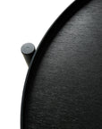 Close-up of the Swivel Tray Side Table by Ethnicraft, a round black wooden table with a raised edge and cylindrical support on the left, from the Tray Collection, shown against a white background.