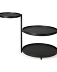 The Ethnicraft Swivel Tray Side Table features three circular black trays at varying heights, slender vertical supports, and an asymmetrical design. Part of the Ethnicraft Tray Collection.