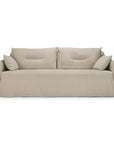 A bone-colored, two-seater Ethnicraft Weave sofa featuring two large back cushions and two side pillows. The sofa showcases a minimalistic design with linen-blend upholstery and a removable slipcover that drapes loosely over the base, extending to the floor.