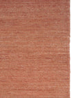 A close-up of the Ethnicraft Nomad Kilim Rug in Terracotta shows the woven texture and rich shade variations of this sheep wool piece, with the fabrics right edge also visible.