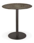 The Blend Dining Table - Ray Whisky by Ethnicraft features a small, round, textured wood-like top and sturdy dark metal pedestal base. Ideal for commercial spaces, interchangeable tops add versatility while the rustic finish contrasts with the sleek base.