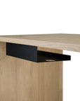 A close-up of a modern wooden desk with an Ethnicraft Metal Cable Tray mounted underneath for organized cable management. The desk features a light, natural wood finish.