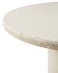Close-up of the Elements Dining Table by Ethnicraft, featuring a round, light beige microcement top with a textured surface and cylindrical base, set against a white background.