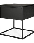 The Monolit Nightstand - Black Oak by Ethnicraft features a modern box-shaped top and open metal frame, blending minimalist design with classic European refinement.