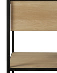 A close-up of the Ethnicraft Monolit Console - Oak shows light solid oak shelves and a black metal frame, with a shelf and a drawer or panel above, combining modern style and functional storage.