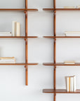 The Ethnicraft PI Wall Shelf - Mahogany (5 shelves) features a minimalist, grid-like design in solid mahogany. Displayed against a white wall, the shelves hold books both upright and flat for a modern look.