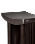 Close-up of the Ethnicraft Roller Max Stool, highlighting its dark wood finish, smooth curved edge, and vertical slats beneath the seat for a modern, elegant look.