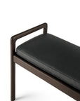 The Ethnicraft Jack Bench – Mahogany with Black Leather features a dark wood frame, one rounded armrest, and a black leather seat, shown against a white background.