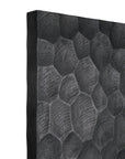 Close-up of the Chopped Room Divider by Ethnicraft, featuring a textured black surface with overlapping hexagon patterns, evoking intricately crafted mahogany and showcasing a striking three-dimensional sculpted look.