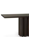 The Sequence Dining Table by Ethnicraft features a modern rectangular design in dark brown mahogany, highlighted by a distinctive geometric base with vertical slats. Shown on a white background.