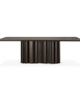 The Sequence Dining Table by Ethnicraft is crafted in dark brown mahogany with a flat top and a sculptural base featuring vertical ridges and a wavy design.