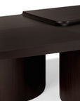 A close-up of the Ethnicraft Brutalist Coffee Table showcases its modern dark wood design, rounded legs, and raised rectangular tray, all set against a white background.