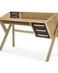 The Origami Desk - Black by Ethnicraft features a modern European oak design with angled legs, three black drawers on the right, two cubby holes on the left, and an open back shelf—blending geometric minimalism with classic refinement.