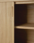 Close-up of the Ethnicraft Roller Max Sideboard in light wood, featuring vertical grooves and a partially open sliding door that reveals two interior shelves.