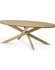 The Mikado Coffee Table Oval by Ethnicraft features a smooth solid oak top and three intersecting angled legs for a sculptural modern look. Shown on a plain white background.